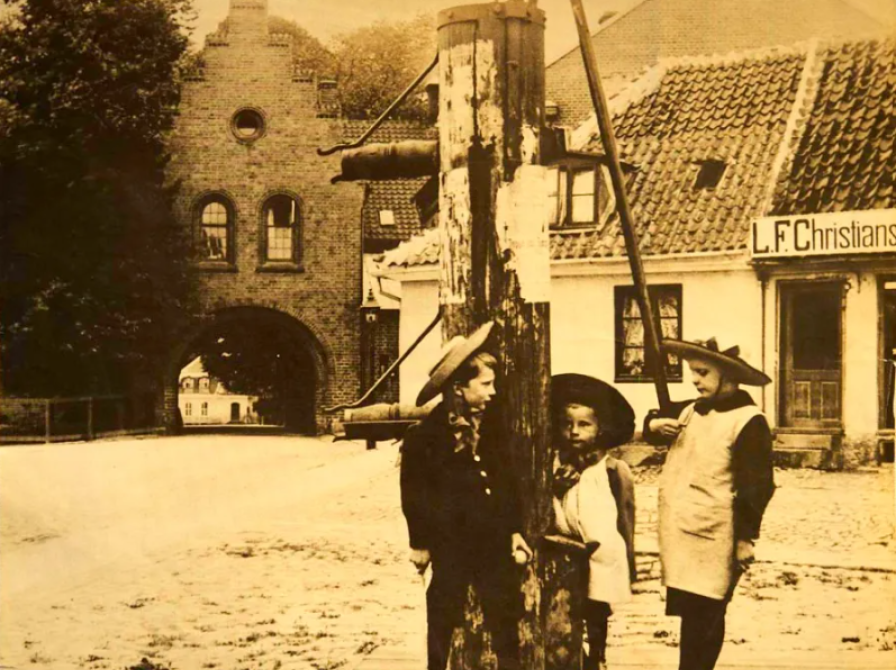 Fotografi af Torvet, 1901. De tre børn står ved Sorøs gamle vandpost på Torvet.  Det lave hus bag vandposten blev kaldt Renaurds Hus. Det blev revet ned i 1912, og materialerne blev brugt til at fylde den gamle brønd op.